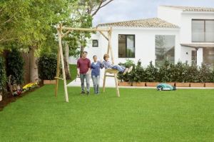 Familie im Garten, im Hintergrund ein Rasenmähroboter